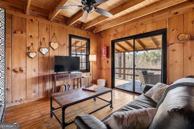 living room featuring light hardwood / wood-style floors, ceiling fan, wooden walls, and beam ceiling