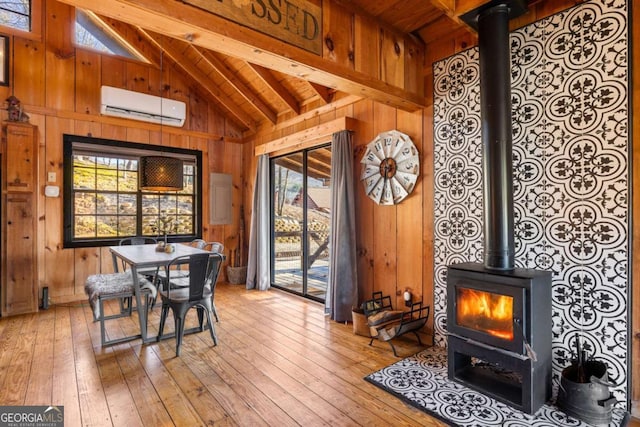 dining room featuring a wall mounted AC, wood walls, and a wood stove