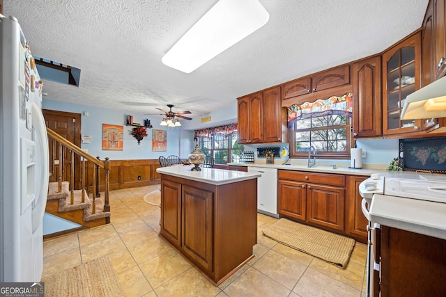 kitchen featuring ceiling fan, sink, light tile patterned flooring, white appliances, and a kitchen island