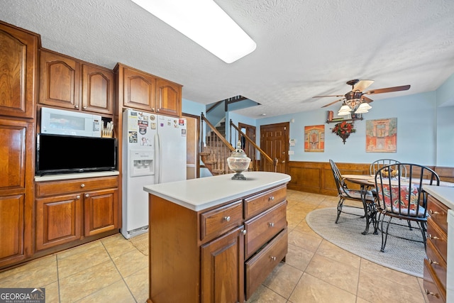 kitchen with a center island, wood walls, white appliances, ceiling fan, and a textured ceiling