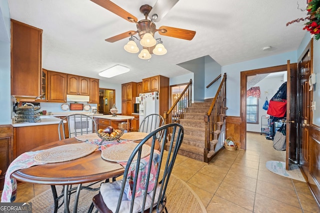 tiled dining space with a textured ceiling and ceiling fan