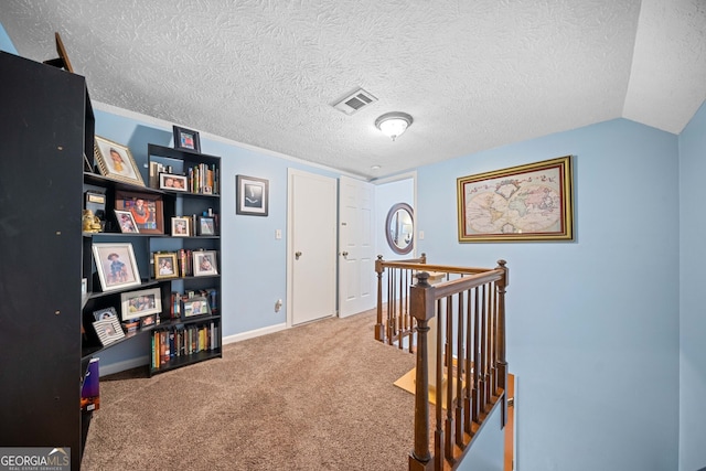 hallway with carpet flooring, a textured ceiling, and vaulted ceiling