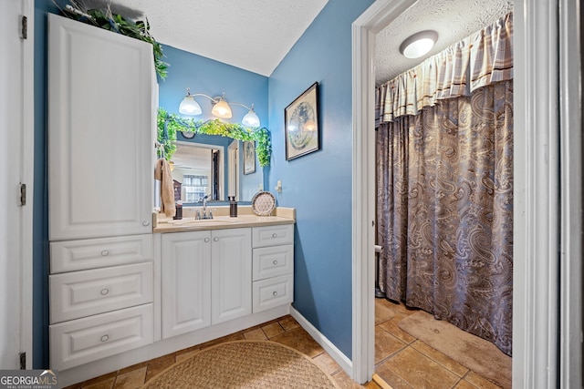 bathroom with tile patterned floors, vanity, and a textured ceiling