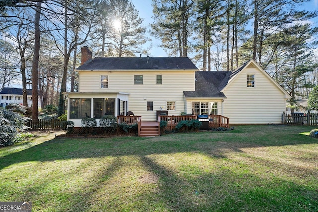 rear view of property with a sunroom, a yard, and a wooden deck