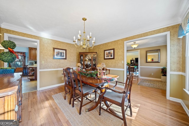 dining area with ornamental molding, a chandelier, and light wood-type flooring