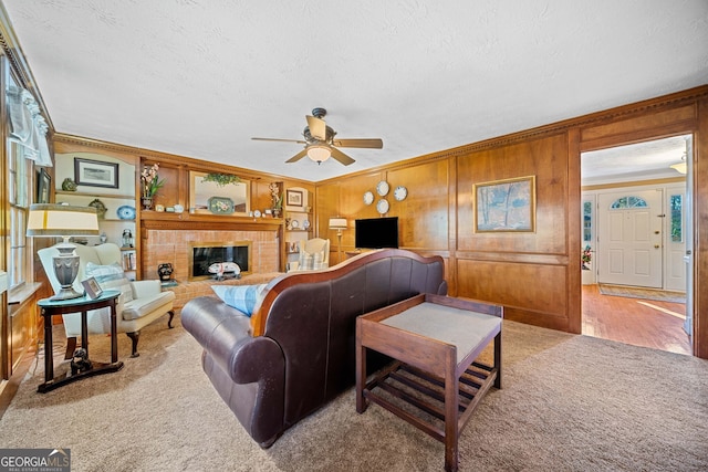 living room featuring wood walls, ornamental molding, light carpet, and a tile fireplace