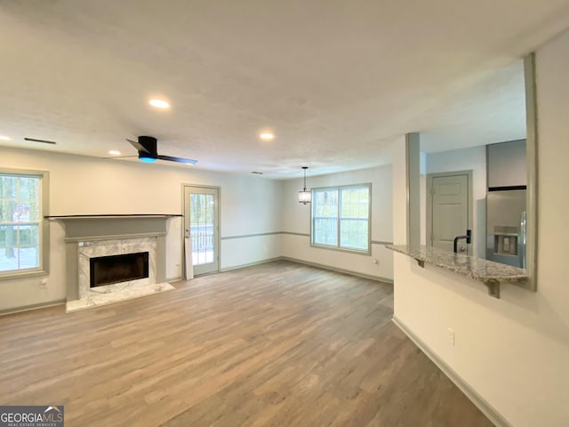 unfurnished living room with hardwood / wood-style flooring, ceiling fan, and a fireplace