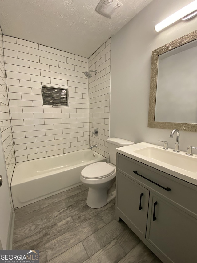 full bathroom featuring toilet, tiled shower / bath, a textured ceiling, vanity, and hardwood / wood-style flooring