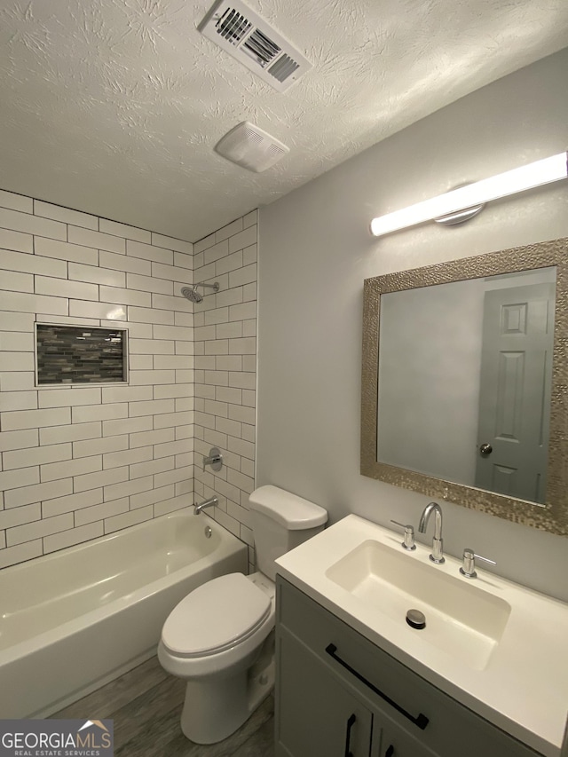 full bathroom with toilet, tiled shower / bath, a textured ceiling, vanity, and hardwood / wood-style flooring