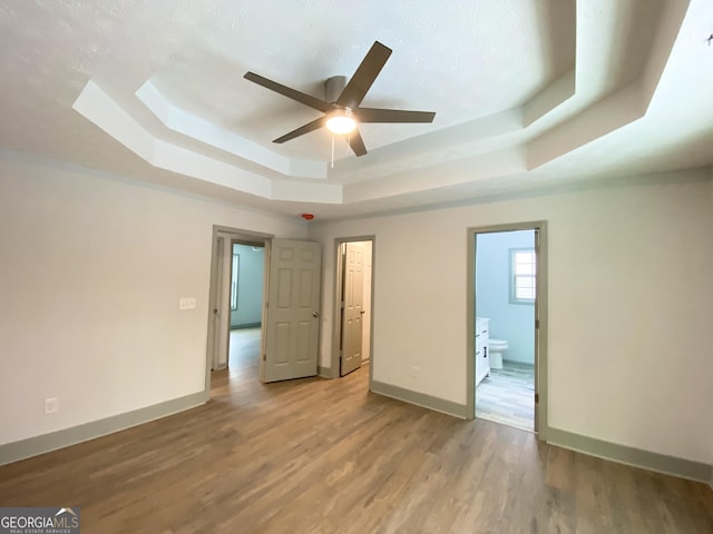 unfurnished room featuring light hardwood / wood-style flooring, a raised ceiling, and ceiling fan