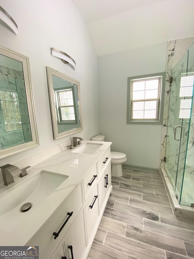 bathroom with a shower with door, vaulted ceiling, vanity, and toilet