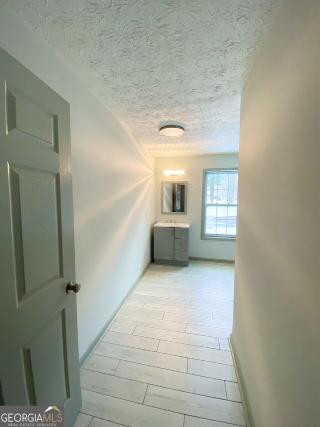 hall featuring sink, a textured ceiling, and light hardwood / wood-style flooring