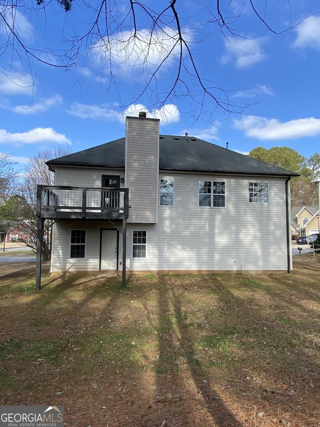 back of house with a deck and a lawn