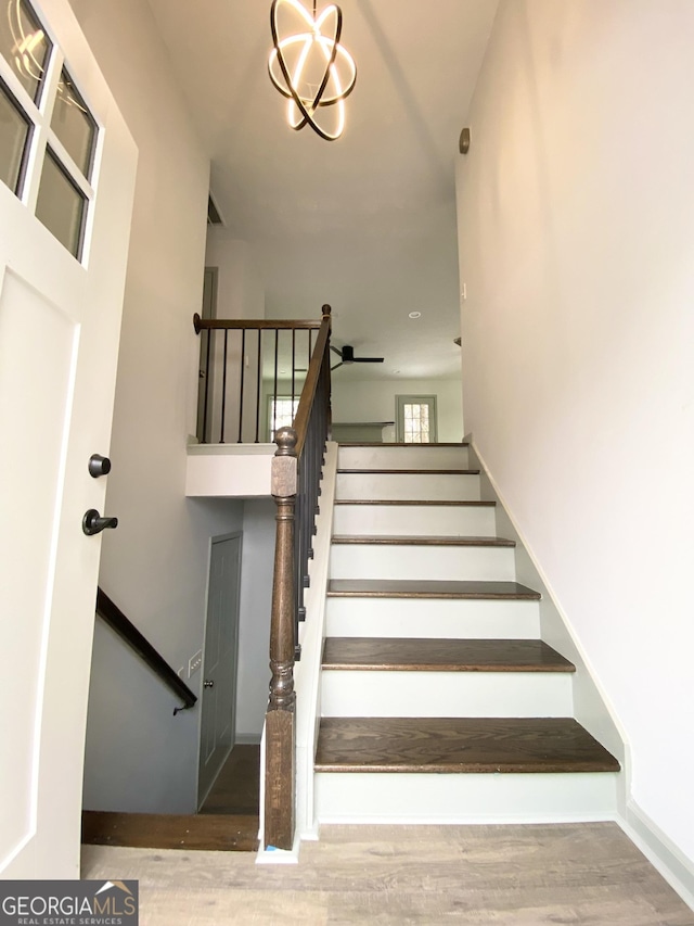 stairway featuring hardwood / wood-style floors and a chandelier