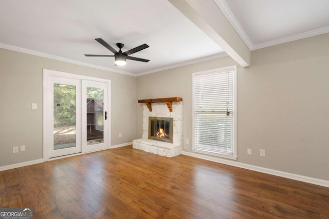 unfurnished living room with hardwood / wood-style flooring, a stone fireplace, ceiling fan, and crown molding