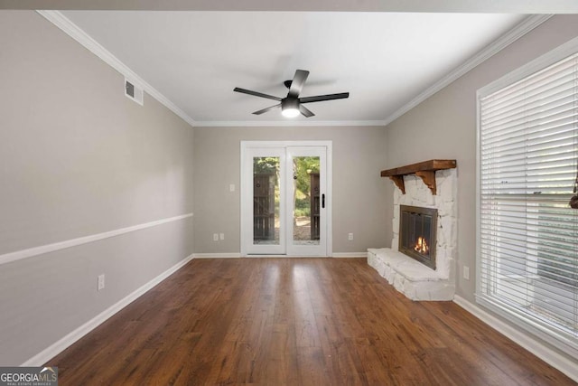 unfurnished living room featuring dark hardwood / wood-style floors, a stone fireplace, ceiling fan, and ornamental molding