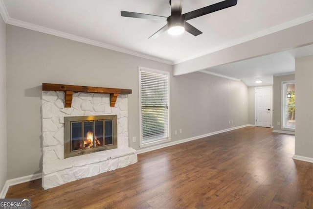 unfurnished living room with a stone fireplace, ceiling fan, dark wood-type flooring, and ornamental molding