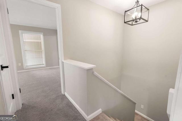 hall featuring carpet floors and a notable chandelier