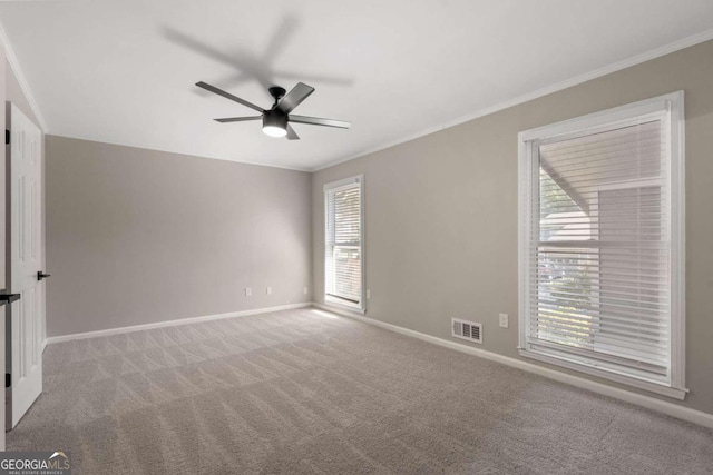 carpeted spare room with plenty of natural light, ceiling fan, and ornamental molding