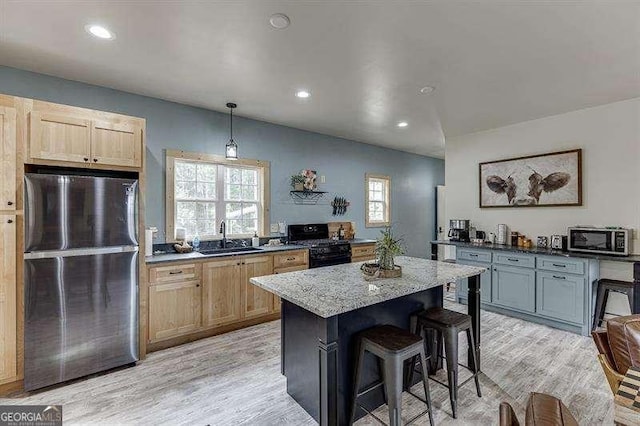 kitchen with a center island, sink, hanging light fixtures, stainless steel appliances, and dark stone countertops