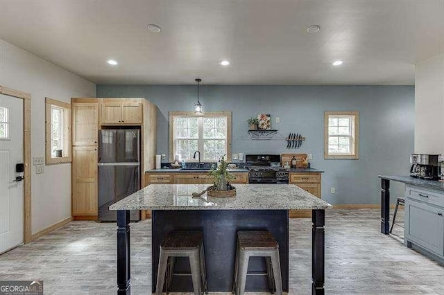 kitchen with black appliances, sink, light stone countertops, decorative light fixtures, and a breakfast bar area