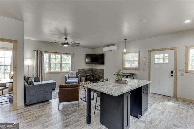 kitchen featuring a wall mounted AC, ceiling fan, pendant lighting, a center island, and light hardwood / wood-style floors