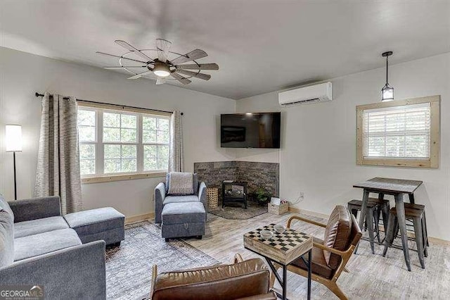 living room with a wood stove, ceiling fan, light hardwood / wood-style floors, and a wall mounted air conditioner