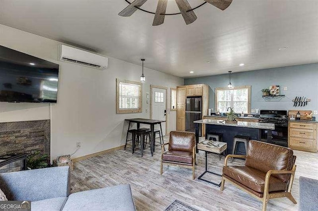 living room with ceiling fan, an AC wall unit, and light hardwood / wood-style flooring