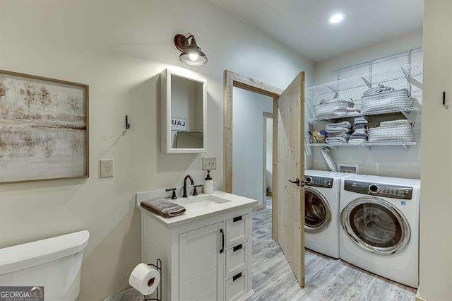 clothes washing area featuring separate washer and dryer, light hardwood / wood-style floors, and sink