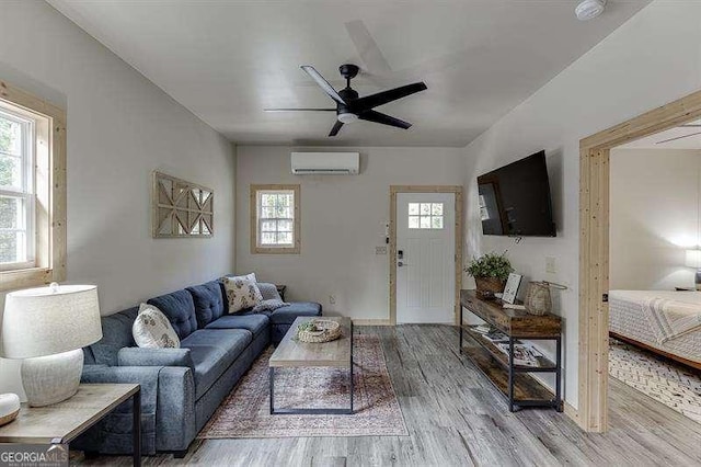 living room featuring hardwood / wood-style flooring, plenty of natural light, a wall mounted AC, and ceiling fan