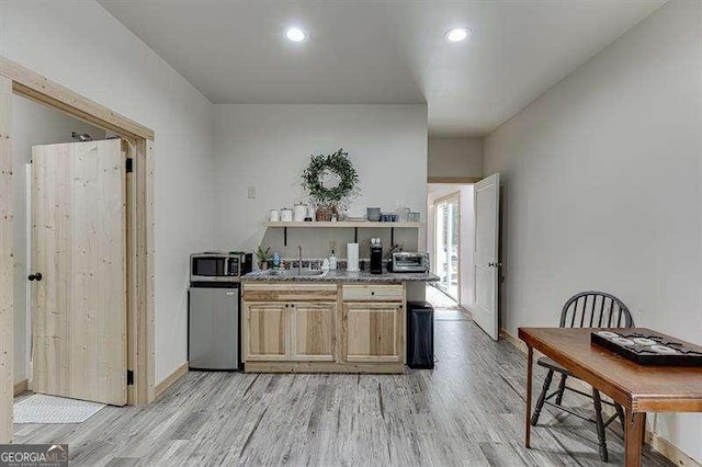 kitchen with light brown cabinets, light wood-type flooring, and sink