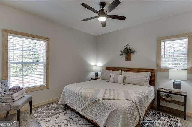 bedroom with multiple windows, ceiling fan, and hardwood / wood-style flooring