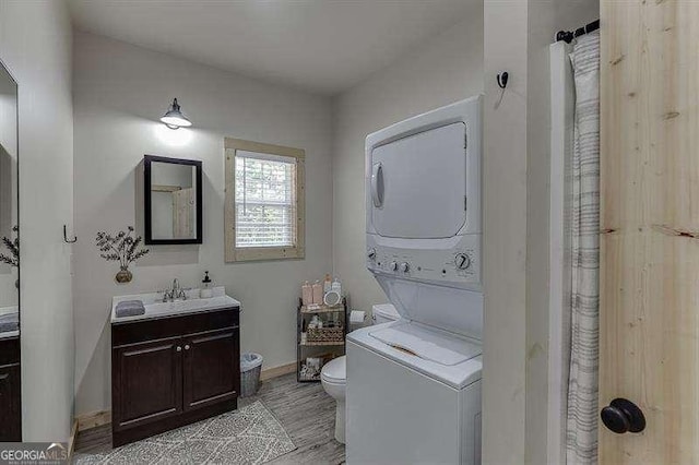 laundry area featuring light wood-type flooring, stacked washing maching and dryer, and sink