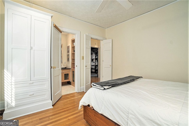 bedroom with a textured ceiling, ceiling fan, a closet, and light hardwood / wood-style flooring