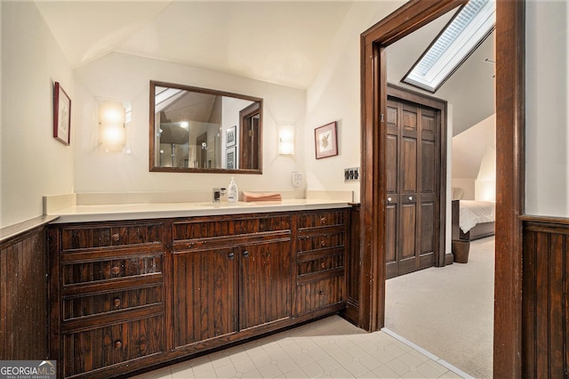 bathroom with lofted ceiling with skylight and vanity