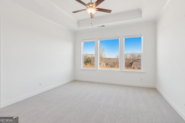 carpeted spare room with ornamental molding, ceiling fan, and a tray ceiling