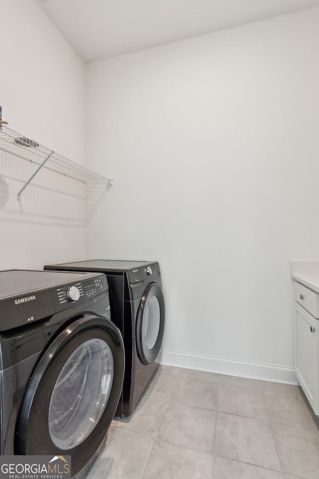 laundry room featuring separate washer and dryer, light tile patterned floors, and cabinets