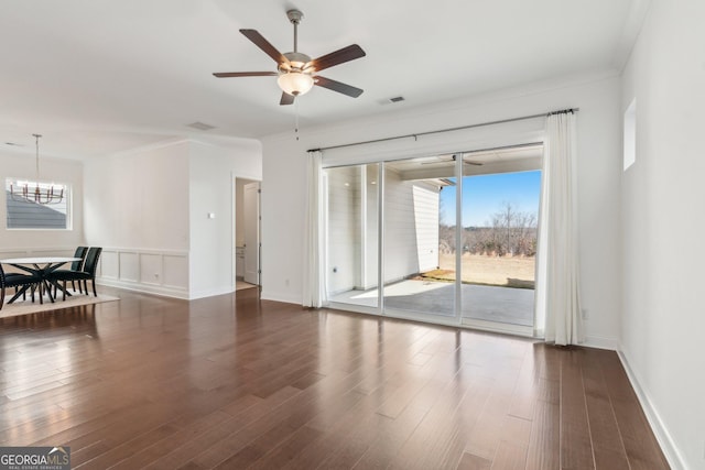 spare room with ornamental molding, ceiling fan with notable chandelier, and dark hardwood / wood-style flooring