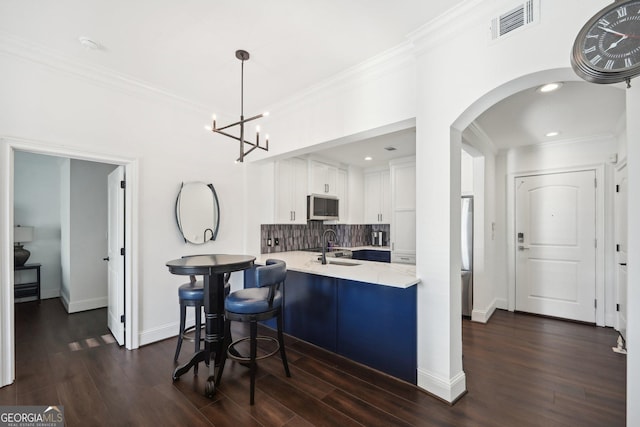 kitchen with decorative backsplash, kitchen peninsula, dark hardwood / wood-style flooring, stainless steel appliances, and white cabinetry