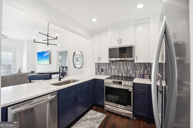 kitchen with decorative backsplash, stainless steel appliances, sink, decorative light fixtures, and white cabinetry