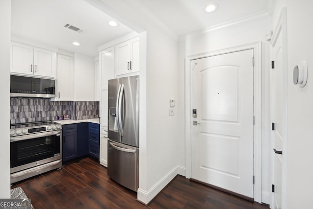 kitchen with dark wood-type flooring, white cabinets, ornamental molding, tasteful backsplash, and stainless steel appliances