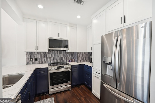 kitchen featuring blue cabinetry, white cabinetry, light stone counters, and appliances with stainless steel finishes