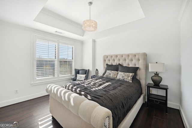 bedroom featuring a tray ceiling, crown molding, and dark wood-type flooring