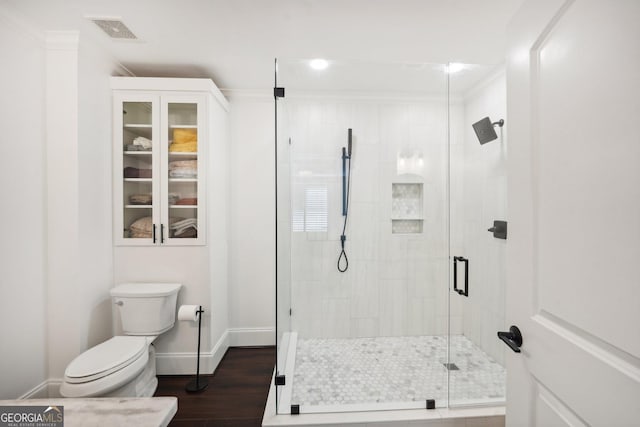 bathroom featuring ornamental molding, hardwood / wood-style flooring, toilet, and a shower with shower door