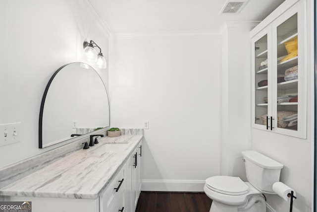 bathroom with toilet, vanity, wood-type flooring, and ornamental molding