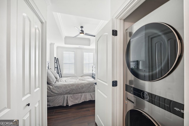 clothes washing area with ceiling fan, ornamental molding, stacked washer / dryer, and dark wood-type flooring