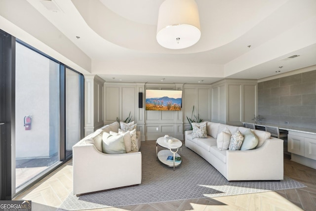 living room featuring a tray ceiling and light parquet flooring