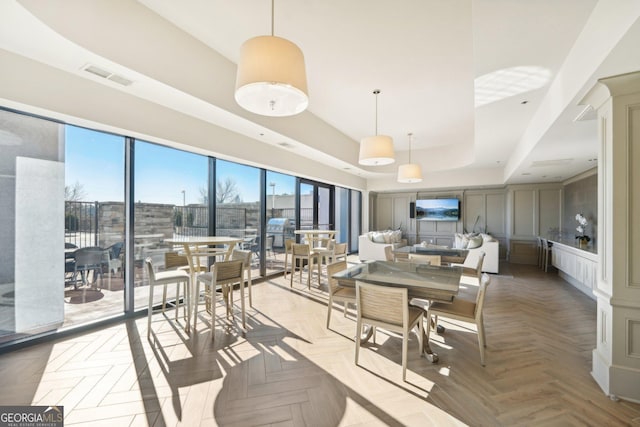 dining area featuring light parquet flooring and a tray ceiling