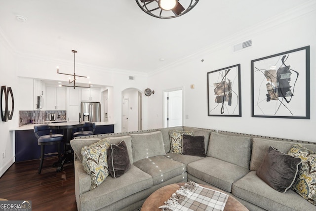 living room featuring a notable chandelier, dark hardwood / wood-style flooring, and ornamental molding