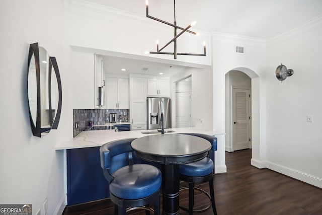 kitchen with kitchen peninsula, stainless steel refrigerator with ice dispenser, backsplash, dark hardwood / wood-style flooring, and white cabinets